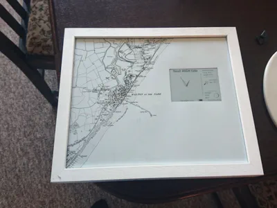 A photo frame containing a map of Walton-on-the-Naze and an electric ink display indicating the next high tide